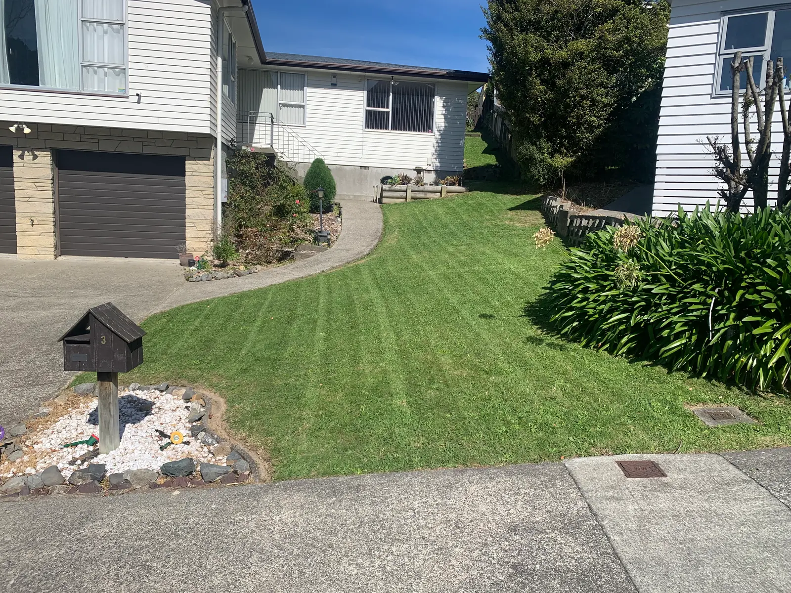 Striped front lawn after mowing, letterbox in the foreground