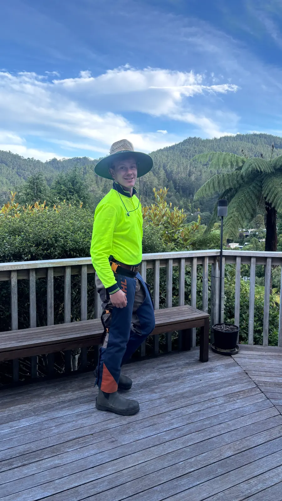 Johnny Batten in hi-vis on a deck with bush-covered hills behind